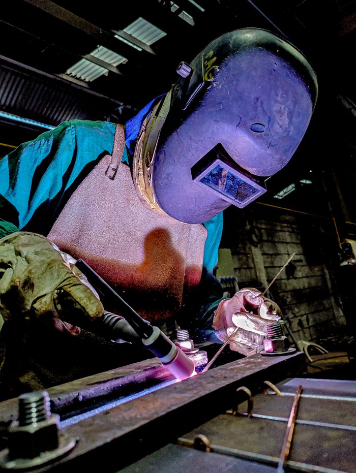 The Art of Drawing Readers In: Your attractive post title goes here Skilled welder wearing protective gear engages in precise welding in a factory environment.