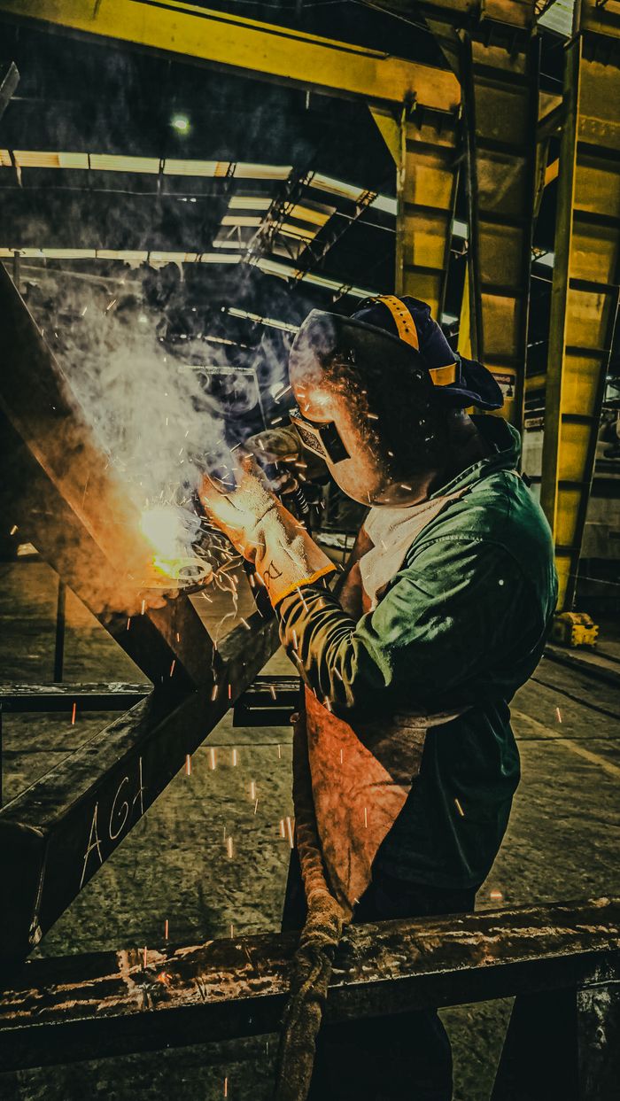 Servicios A skilled welder works on metal fabrication in a Brazilian factory, showcasing industrial precision.