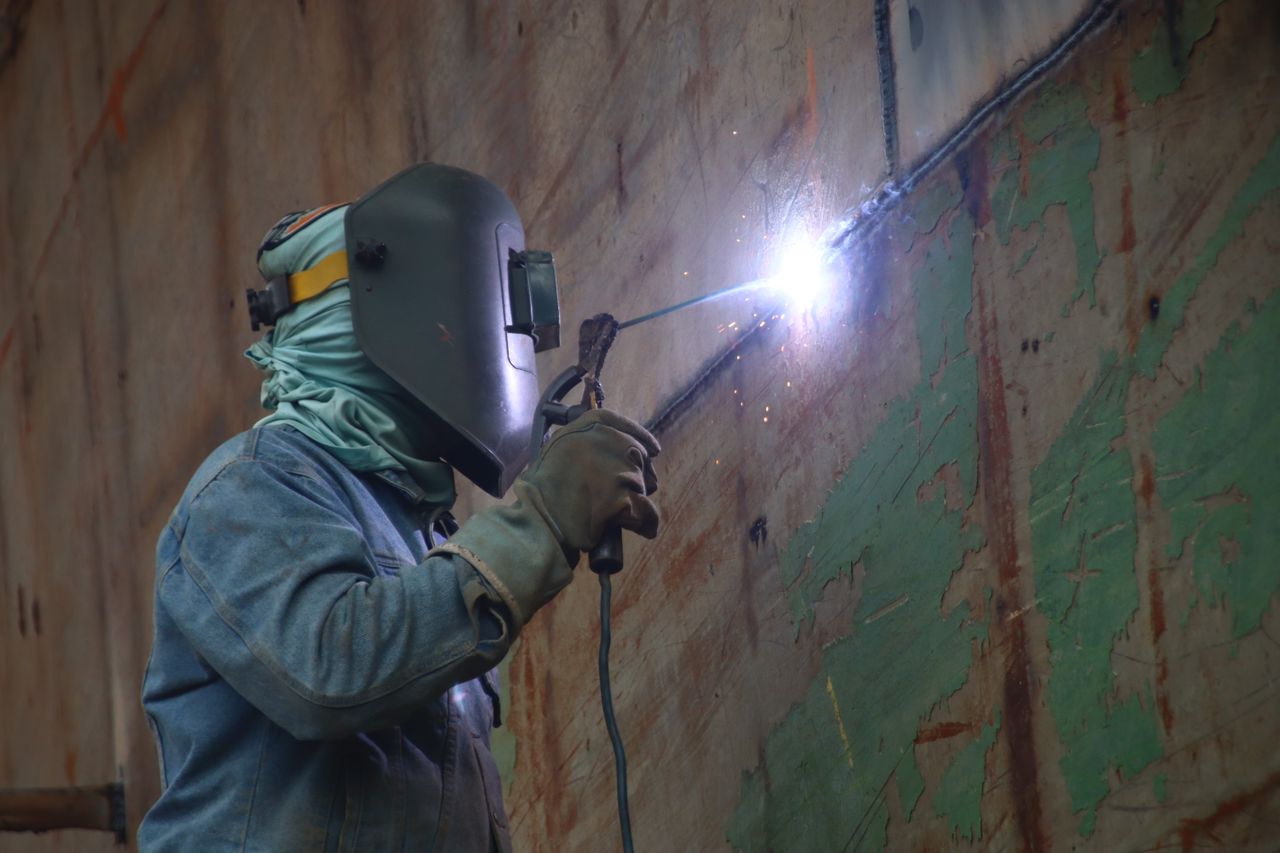 Servicios A welder works in a Keraniganj shipyard, highlighting industrial labor's skilled techniques.