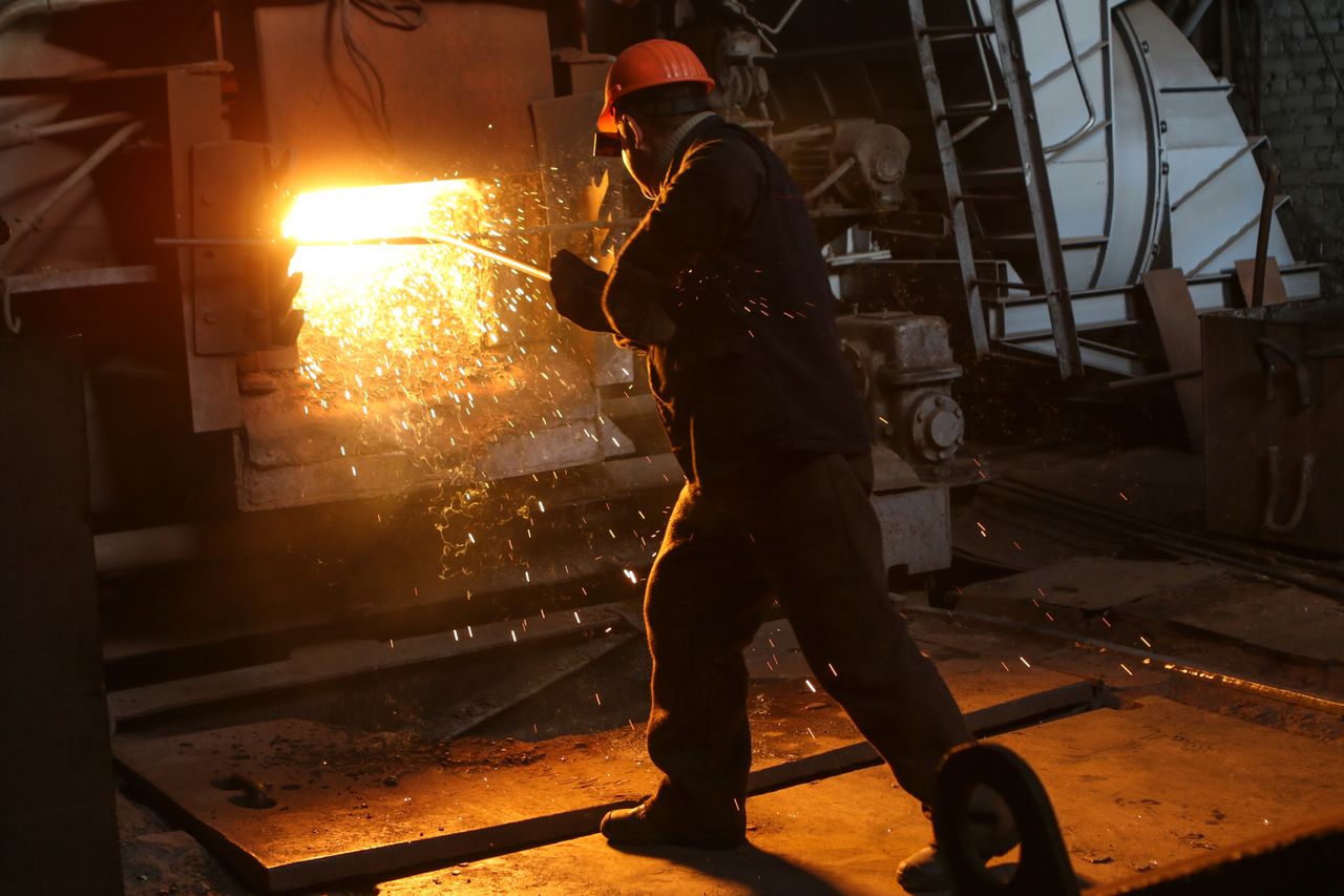 Servicios A worker in protective gear welds metal in an industrial plant with sparks flying.
